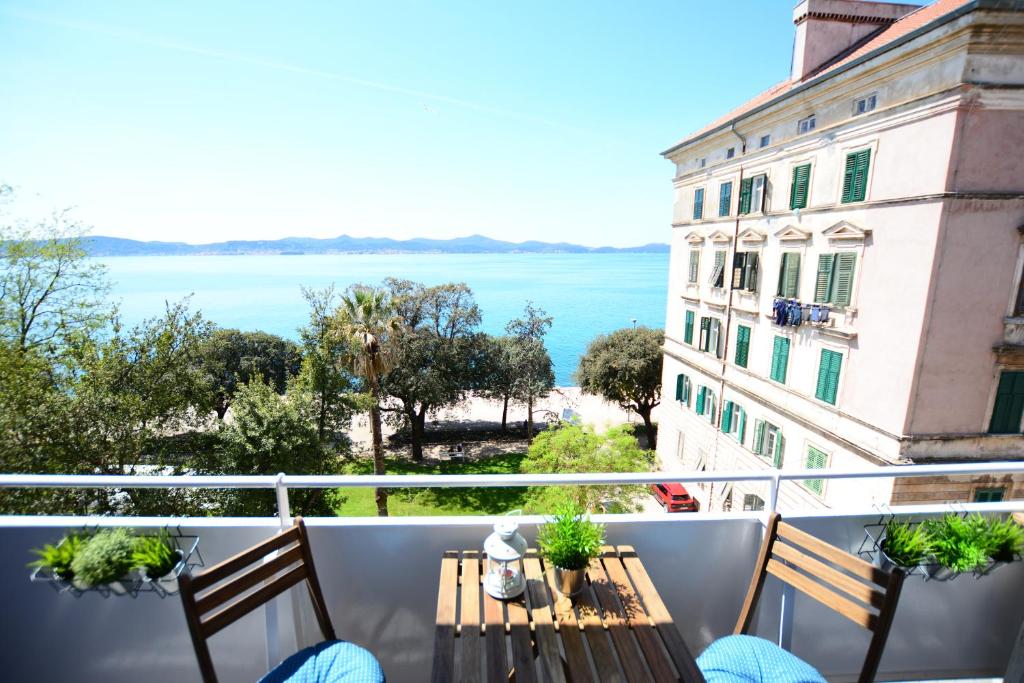 Un balcón con mesa y sillas y vista al mar. en Nora Rooms, en Zadar