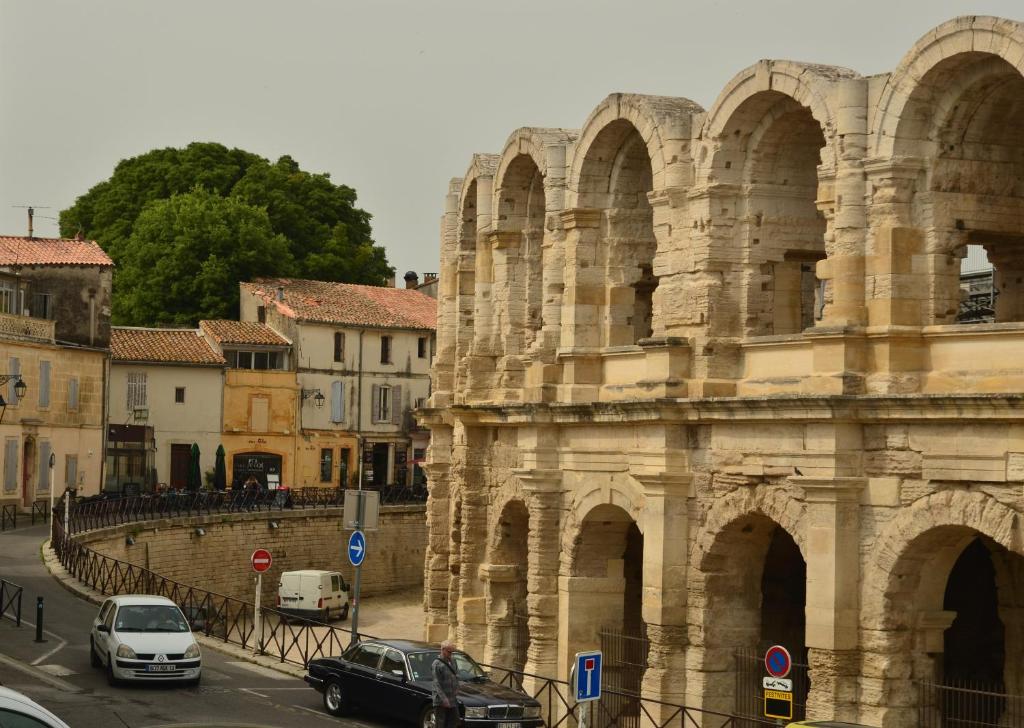 un ancien bâtiment avec des voitures garées devant dans l'établissement la pitchoun des Arènes, à Arles