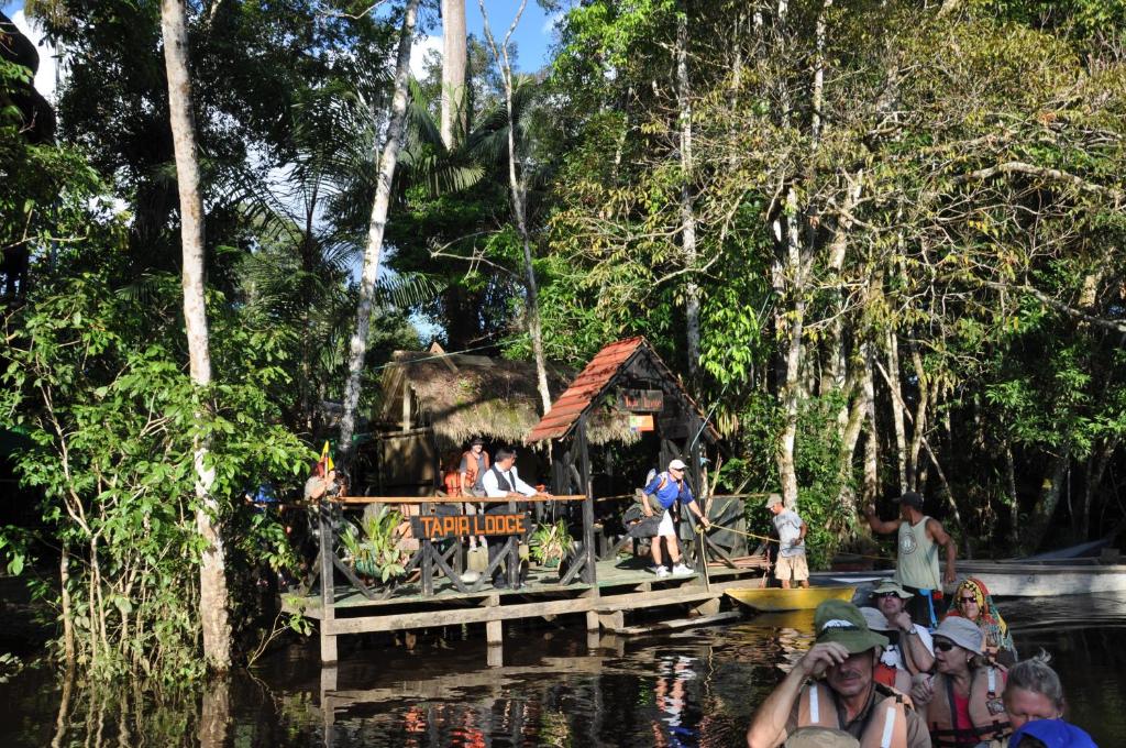 un grupo de personas de pie en un puente en el agua en Tapir Lodge, en Marian