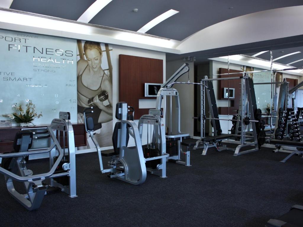 A mirrored fitness room with cardio and resistance equipment.