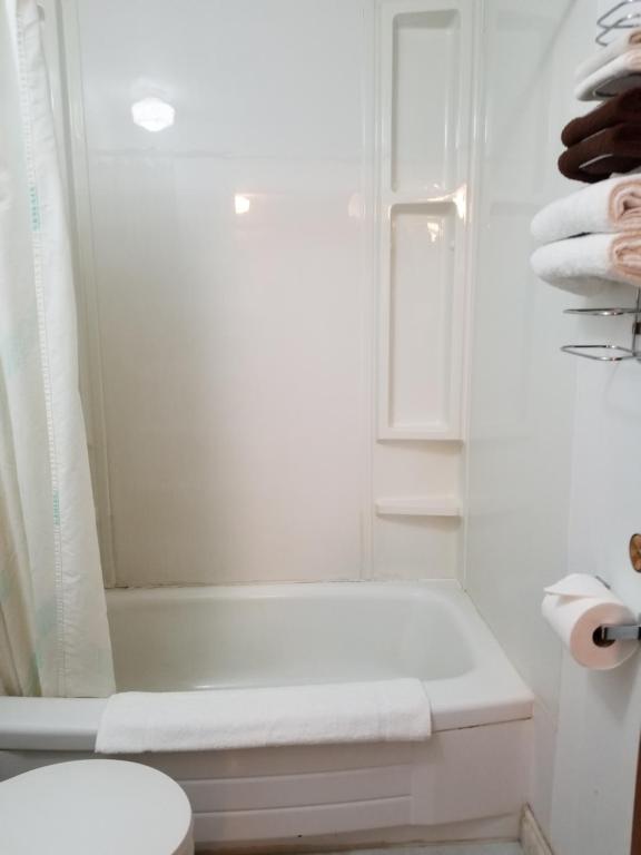a white bathroom with a tub and a toilet at Melsask Motel in Melville