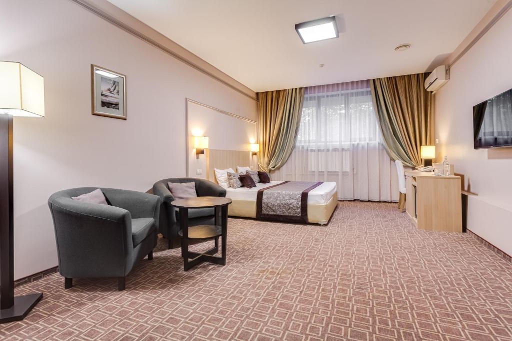 pokój hotelowy z łóżkiem, kanapą i krzesłami w obiekcie Hotel Leon Spa w Moskwie