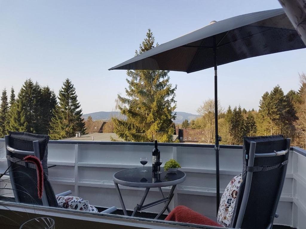 a table and chairs on a balcony with an umbrella at Weitblick in Sankt Andreasberg