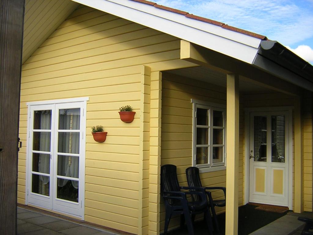 awning on the side of a yellow house with chairs at Fördefarm-Natura in Westerholz