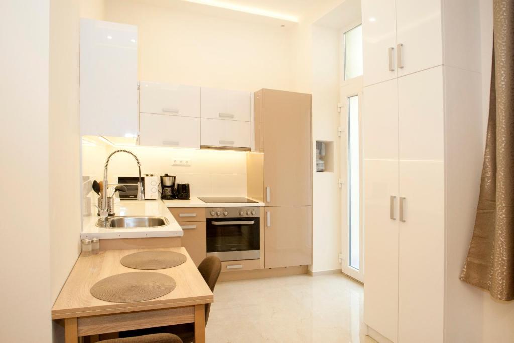 ブダペストにあるRoxana apartmentsの白いキッチン(シンク、カウンタートップ付)