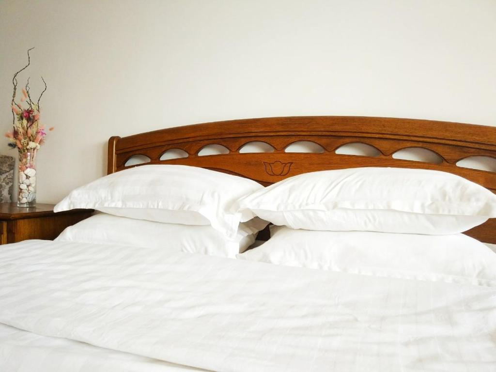 a bed with white pillows and a wooden headboard at Loftik Apartments Abay street in Almaty