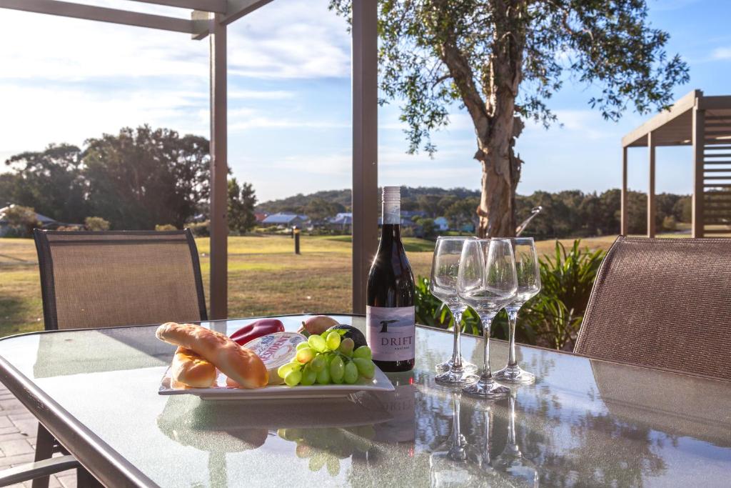 einen Tisch mit einem Teller Essen und einer Flasche Wein in der Unterkunft Condo 105 @ Horizons Golf Resort - Salamander Bay NSW in Salamander Bay