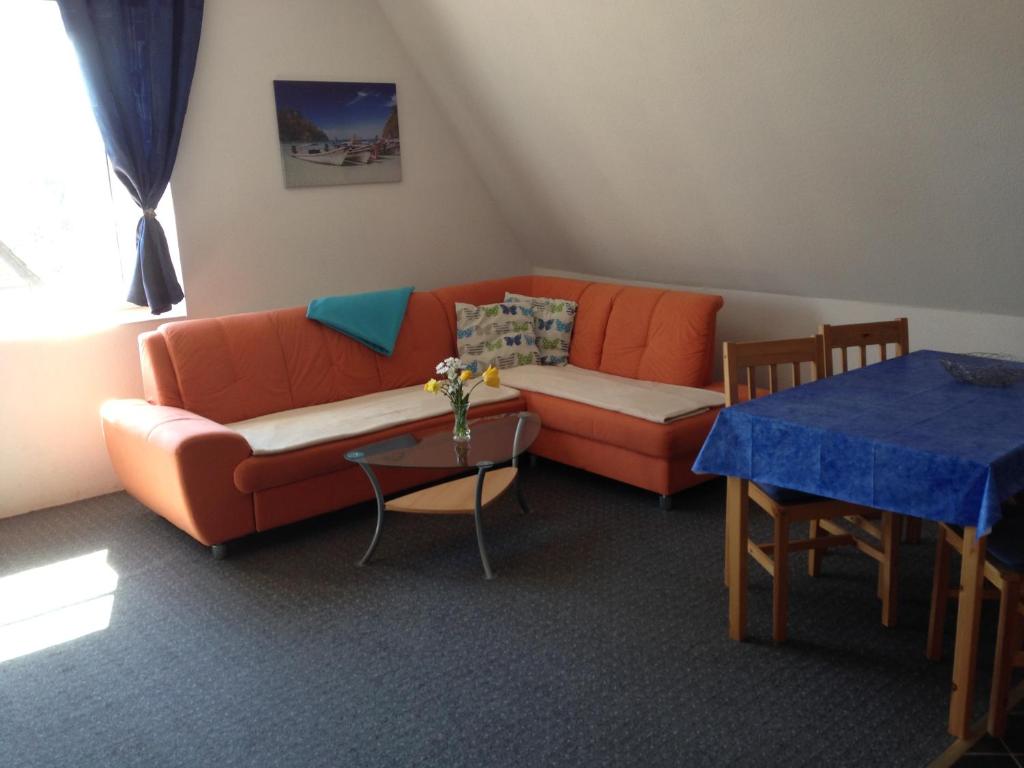 ボルテンハーゲンにあるFerienwohnung Möweのリビングルーム(オレンジ色のソファ、テーブル付)