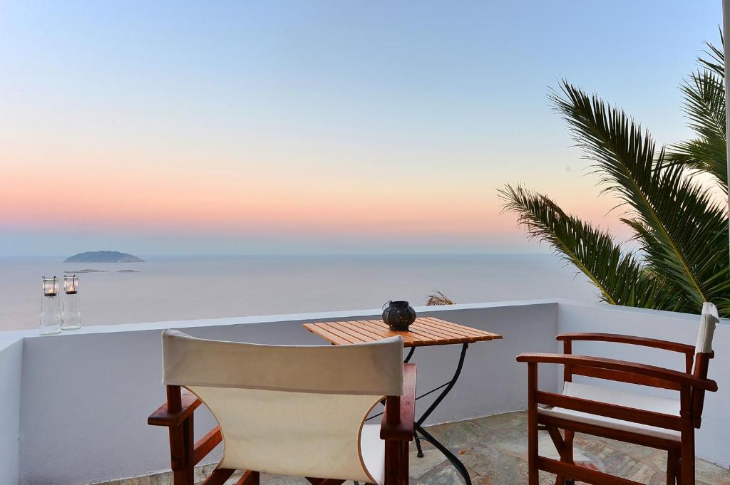 a table and chairs on a balcony with a view of the ocean at Maki House in Anafi