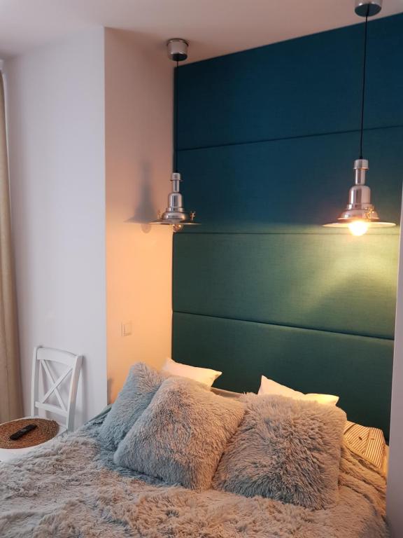 a bedroom with a bed with a green headboard and lights at Amko Style Apartamenty Róża Wiatrów Willa Nord in Jastrzębia Góra