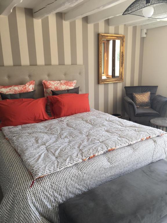 um quarto com uma cama com almofadas vermelhas e uma cadeira em Au Bord de La Dhuy em Orges