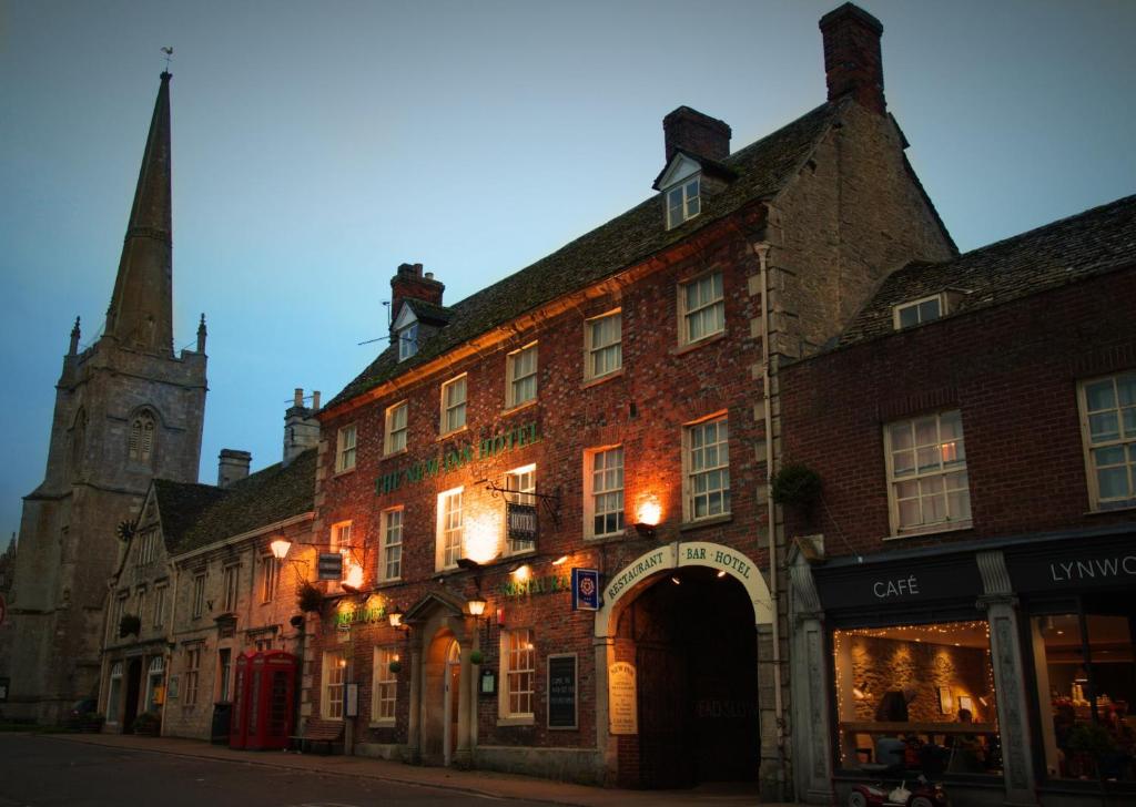 an old brick building on a street with a church at New Inn Hotel in Lechlade