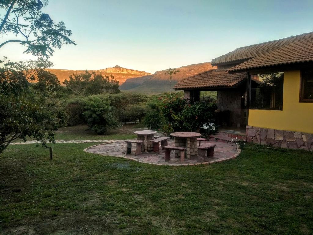 uma mesa de piquenique num quintal com montanhas ao fundo em Pousada Terras do Poente em Vale do Capão