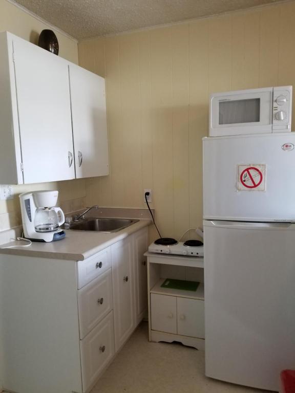 a kitchen with a white refrigerator and a sink at Melsask Motel in Melville