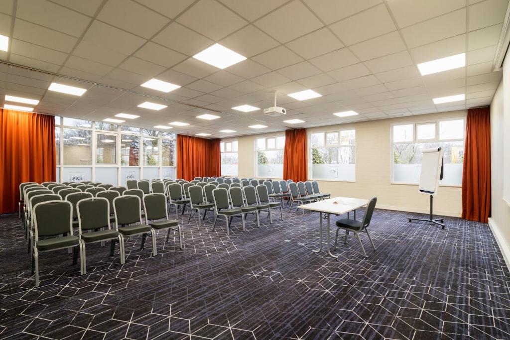 a conference room with chairs and a table and a podium at ibis Rotterdam Vlaardingen in Vlaardingen