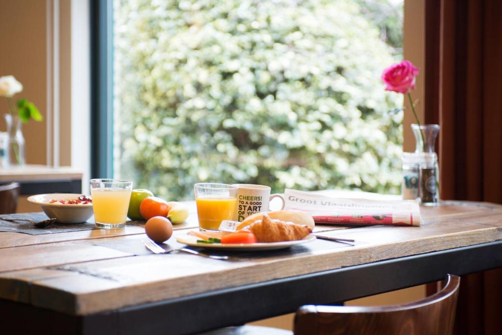 a table with a plate of food and glasses of orange juice at ibis Rotterdam Vlaardingen in Vlaardingen