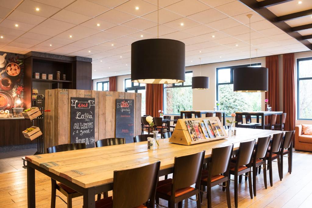 a dining room with a large wooden table and chairs at ibis Rotterdam Vlaardingen in Vlaardingen