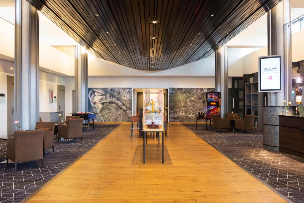 a lobby of a hotel with tables and chairs at ibis Rotterdam Vlaardingen in Vlaardingen