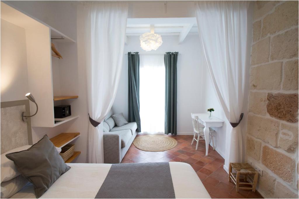 a bedroom with a bed and a couch and a table at My Rooms Ciutadella Adults Only by My Rooms Hotels in Ciutadella