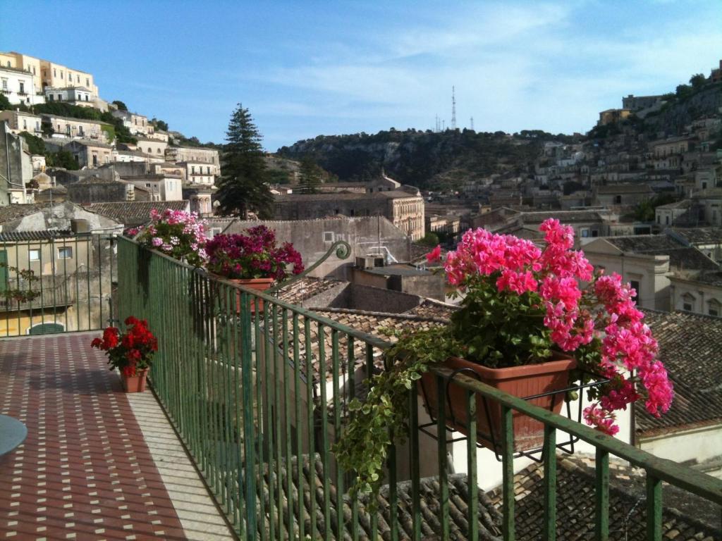 a balcony with pink flowers on a hill at I Tetti di Siciliando in Modica