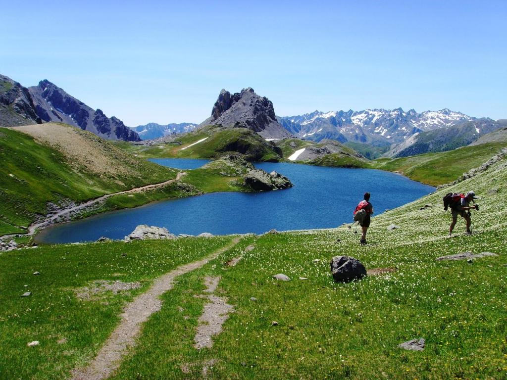 two people walking on a grassy hill with a lake at Rock Noir & Spa in La Salle-les-Alpes