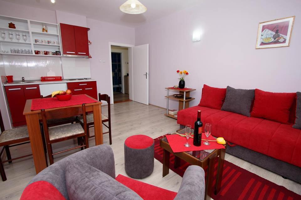 a living room with a red couch and a kitchen at Apartman "Nina" in Soko Banja