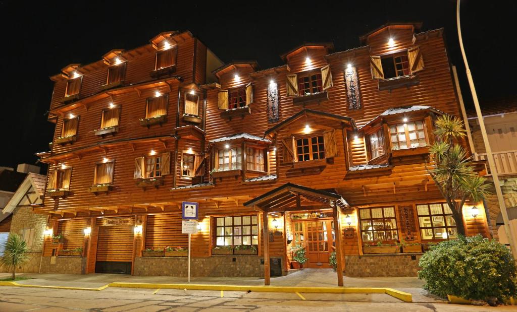 um grande edifício de madeira com muitas janelas à noite em Hosteria Sirenuse em Mar del Plata