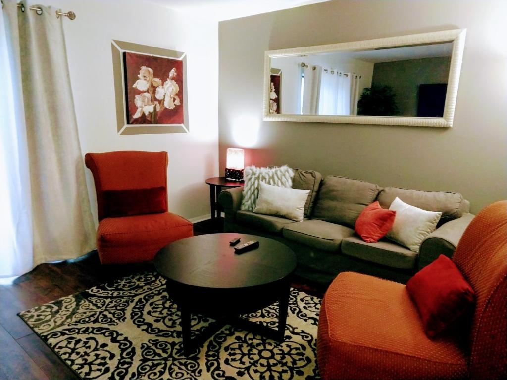 Exclusive Townhome - Central Raleigh Location في رالي: غرفة معيشة مع أريكة وكراسي ومرآة