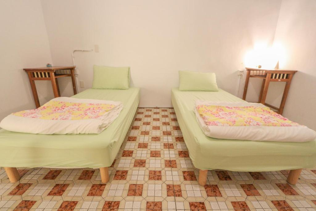 two twin beds in a room with a tiled floor at T-Life Hostel in Longjing