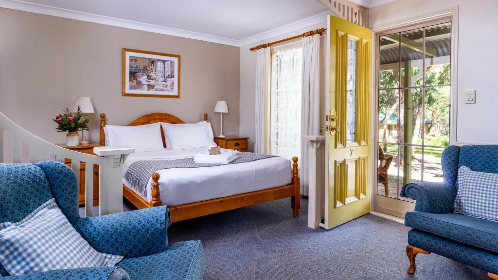 une chambre d'hôtel avec un lit et deux chaises dans l'établissement Honeysuckle Cottages, à Stanthorpe