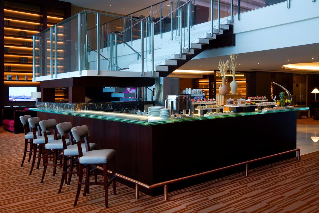 a restaurant with a bar with stools and a staircase at Bab Al Qasr Residence in Abu Dhabi