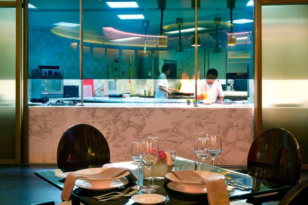 a restaurant with a table with chairs and a chef in the kitchen at Bab Al Qasr Residence in Abu Dhabi