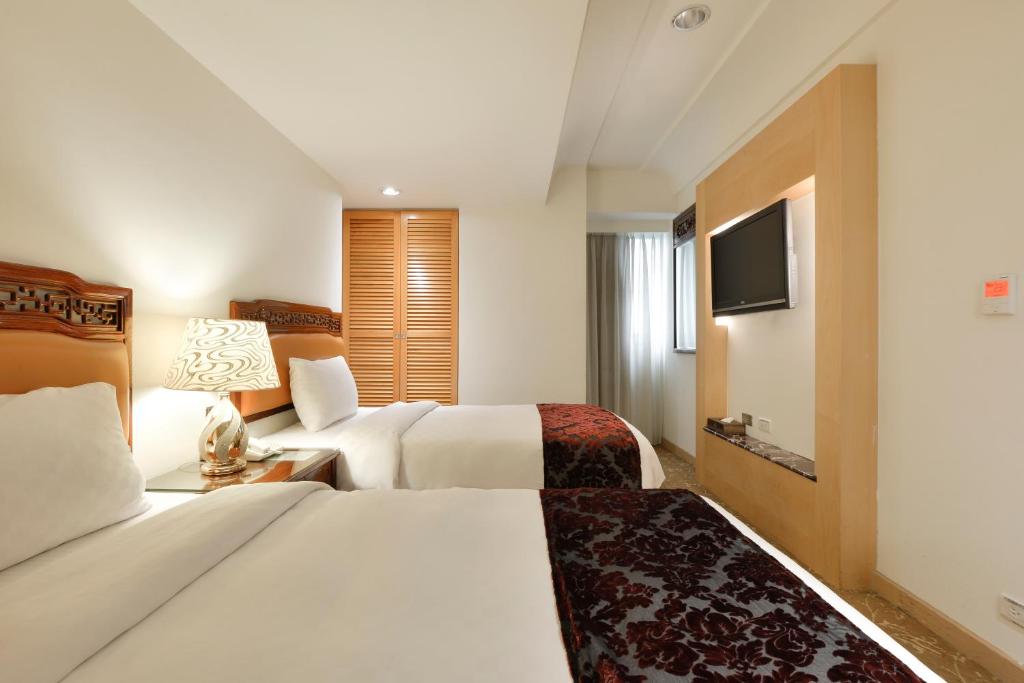 a hotel room with two beds and a television at Hotel Sunshine in Kaohsiung