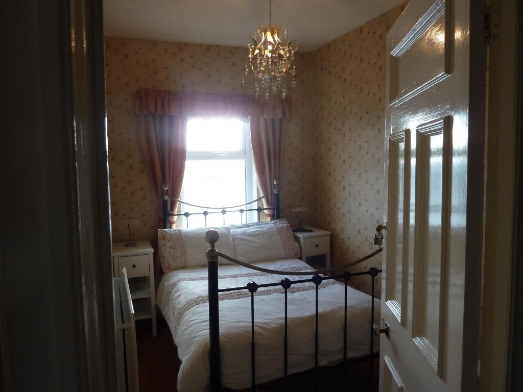 a bedroom with a bed with a chandelier and a window at Captains Lodge in Newbiggin-by-the-Sea