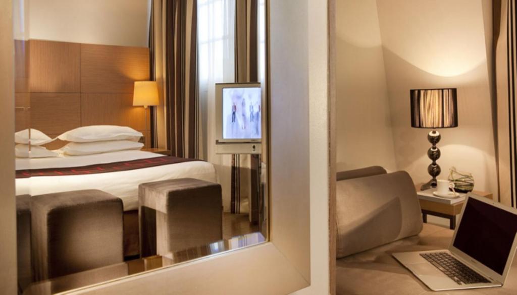 a hotel room with a bed and a desk with a laptop at Villathena in Paris