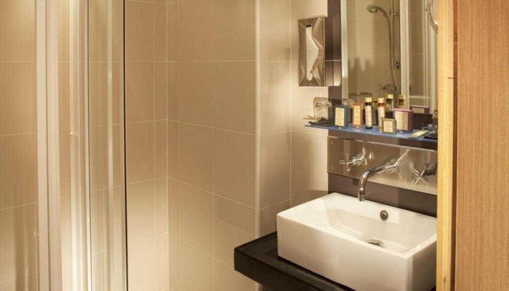 a bathroom with a white sink and a shower at Villathena in Paris