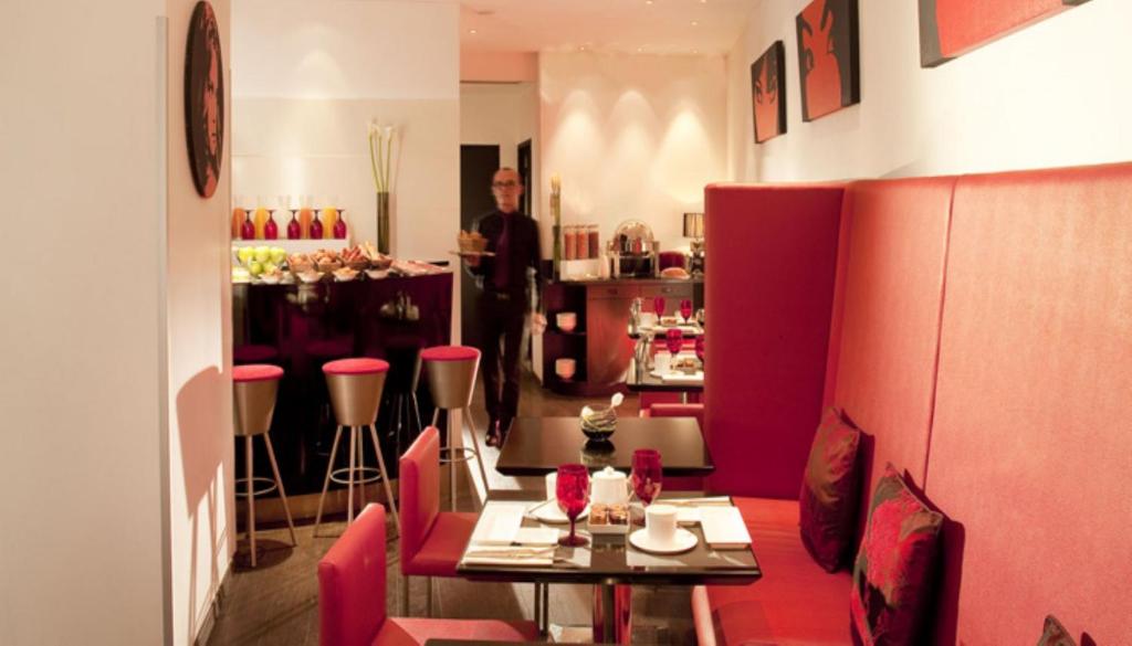 a man standing in a restaurant with a table and chairs at Villathena in Paris