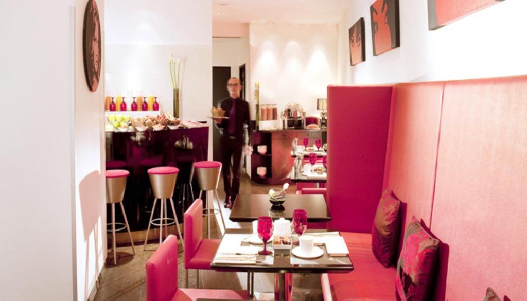 a man standing in a restaurant with a table and chairs at Villathena in Paris