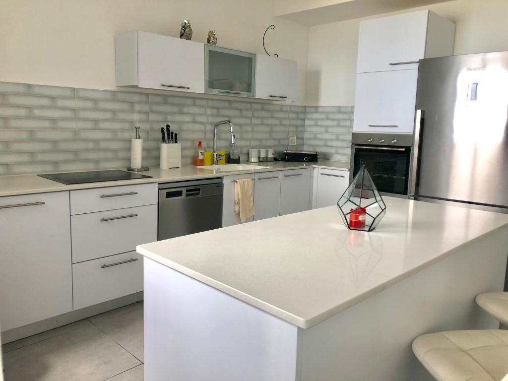 una cucina con armadi bianchi e piano di lavoro bianco di Panorama Apartment " City Garden " a Bat Yam