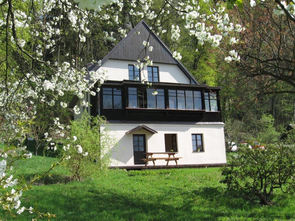 una casa blanca con un banco en un jardín en Apartment Panteon Basecamp en Malá Skála