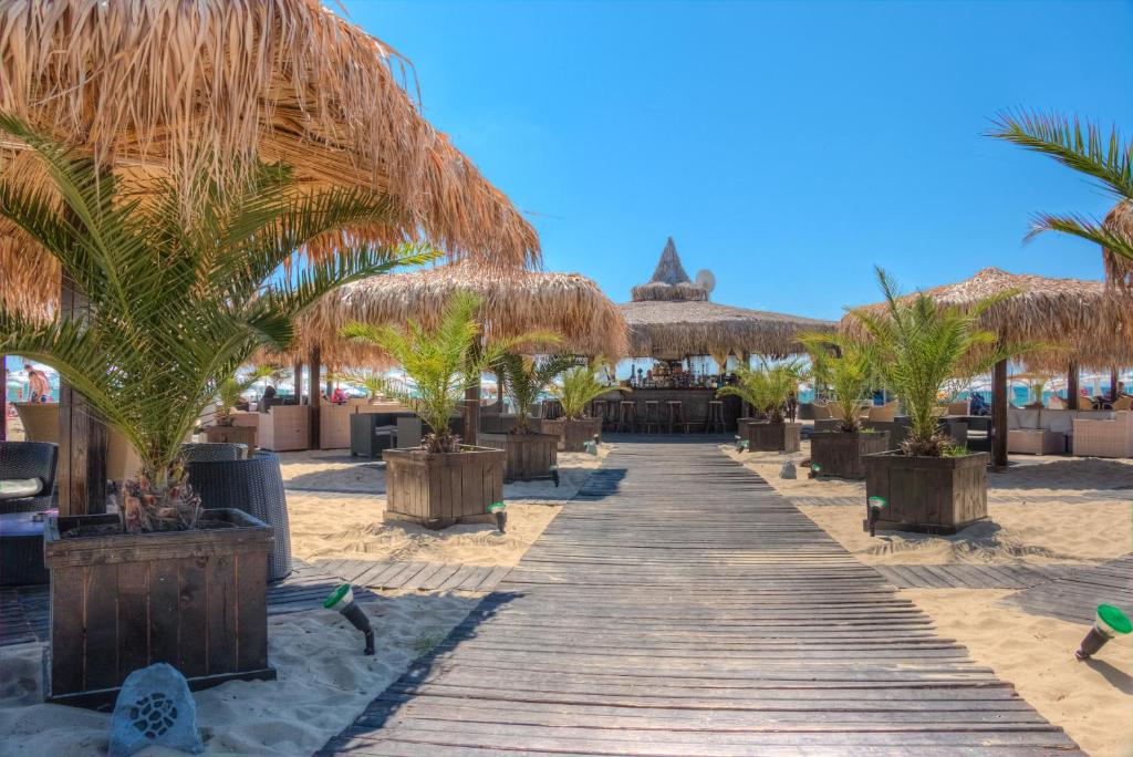 a boardwalk on the beach with palm trees and a resort at Platinum Hotel & Casino in Sunny Beach
