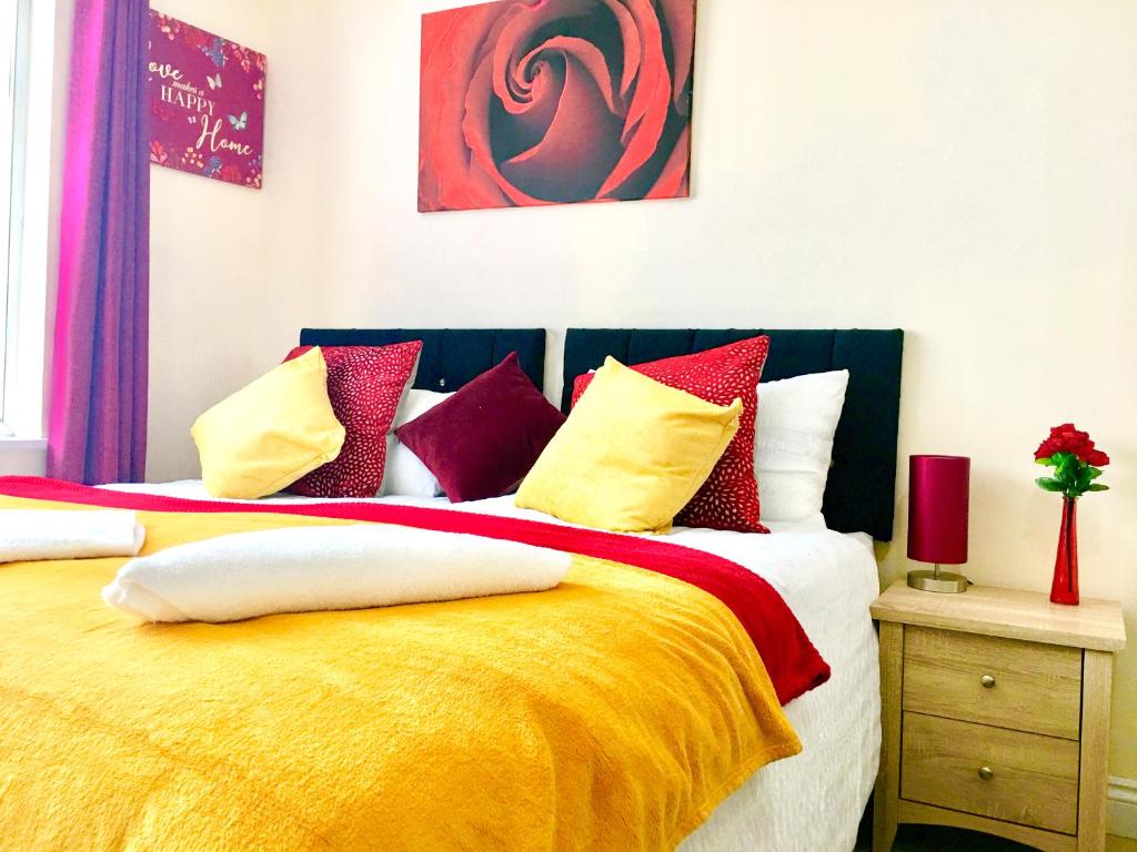 a bedroom with a large bed with colorful pillows at London Luxury Apartment, Private Bathroom in Ilford