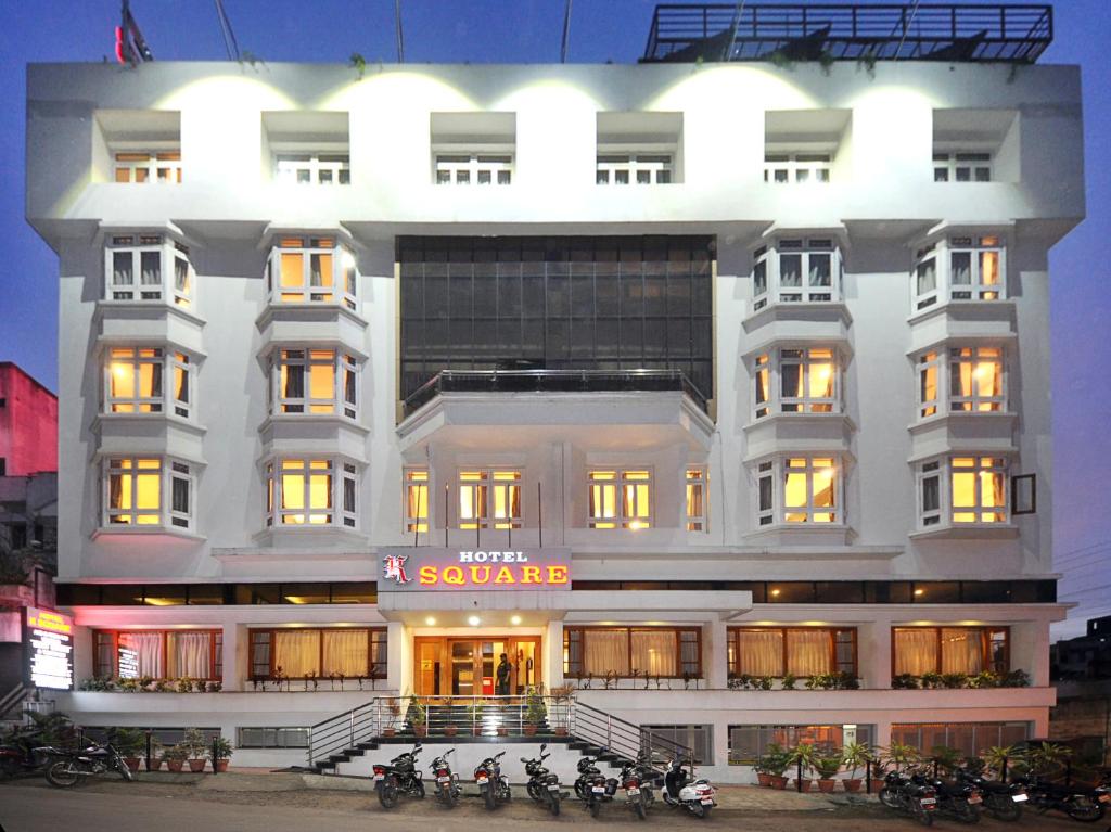 a white building with motorcycles parked in front of it at Hotel K Square in Kolhapur