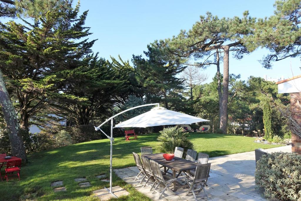 um pátio com uma mesa e um guarda-chuva em A l'Ombre des Pins em La Baule