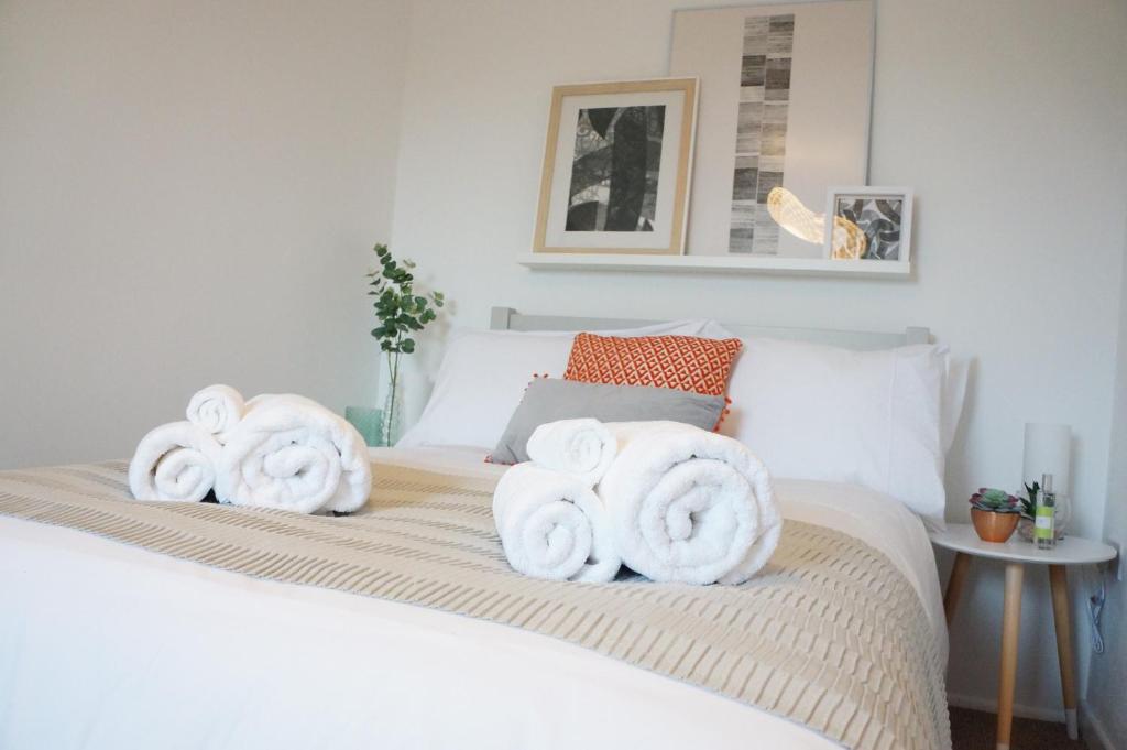 łóżko z białymi ręcznikami na górze w obiekcie The Oldbrook Apartment w mieście Milton Keynes
