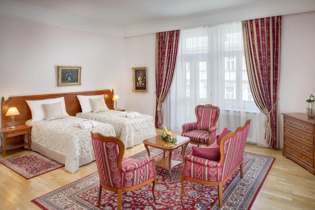 a bedroom with a bed and two chairs and a table at Boutique Hotel Seven Days in Prague