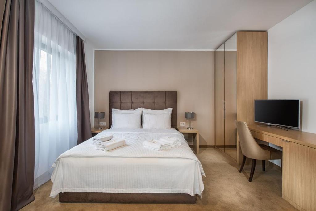 a bedroom with a bed with a desk and a television at Miznah Hotels & Resorts in Bačka Topola