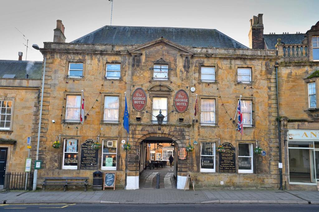 a large brick building with an archway at The George Hotel in Crewkerne