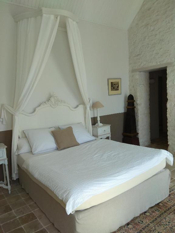 a bedroom with a white bed with a canopy at Le Moulin de la Borderie in Saint-Pierre-dʼOléron