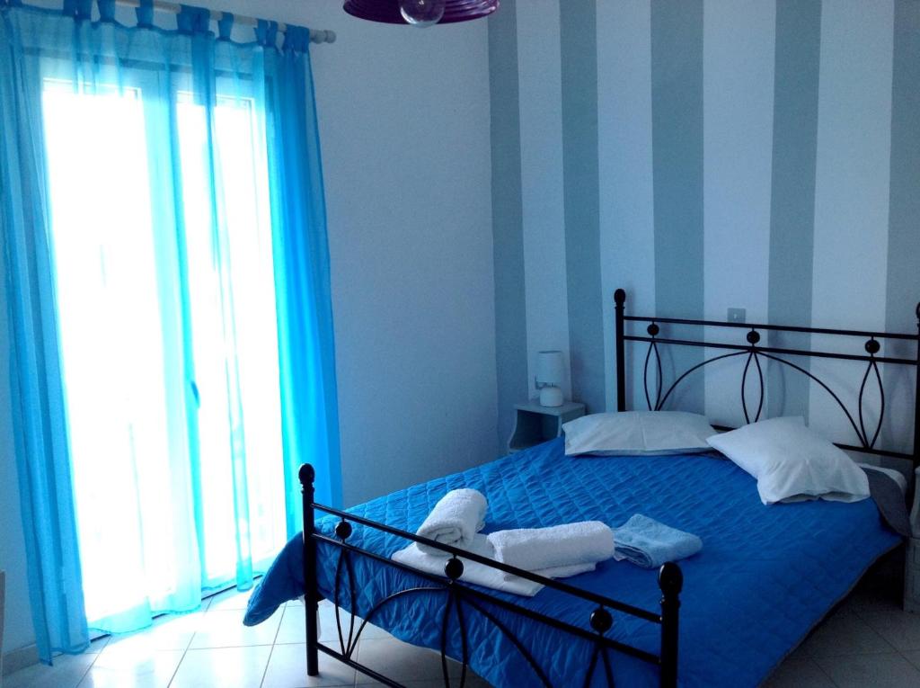 Un dormitorio con una cama con paredes azules y una ventana en ELEFTHERIA rooms, en Livadion